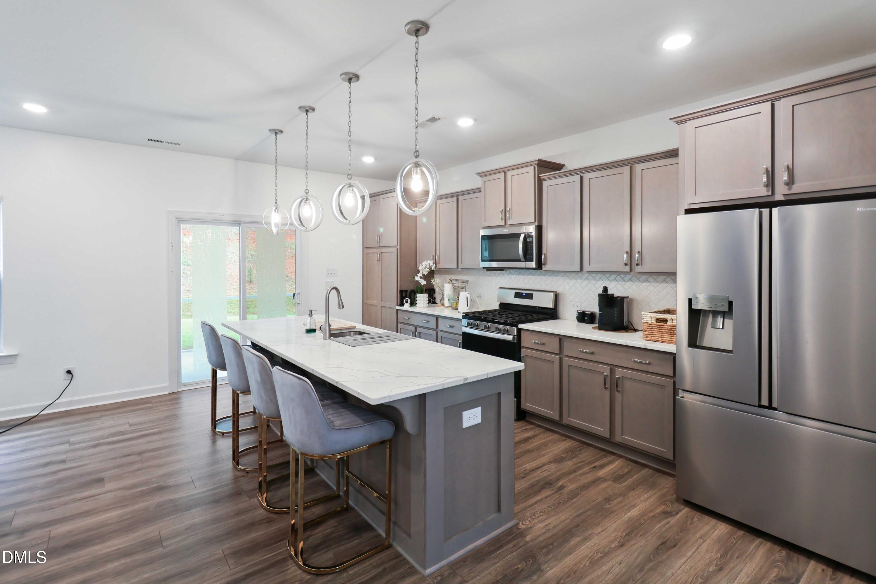 396 Bent Willow Drive Clayton, NC 27527 - Photo 12 of 36 a kitchen with kitchen island wooden floors white appliances and chairs