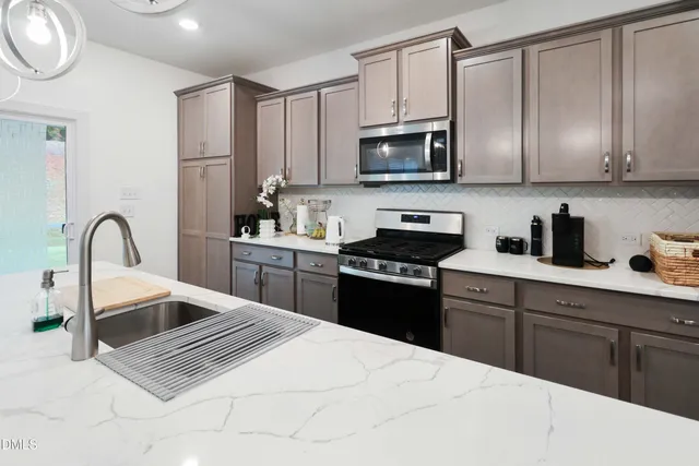 a kitchen with stainless steel appliances granite countertop a stove a sink dishwasher and a microwave oven with cabinets