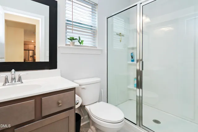 a bathroom with a shower sink vanity mirror and toilet