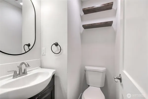 a bathroom with a toilet sink vanity and mirror