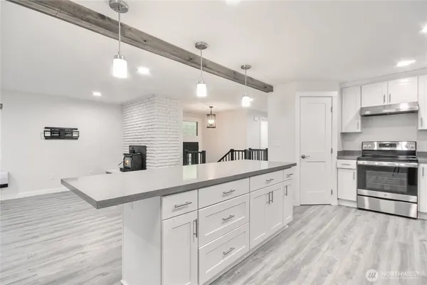 a large white kitchen with a large window a sink and stainless steel appliances
