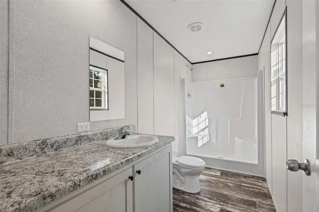 a bathroom with a granite countertop sink toilet and shower