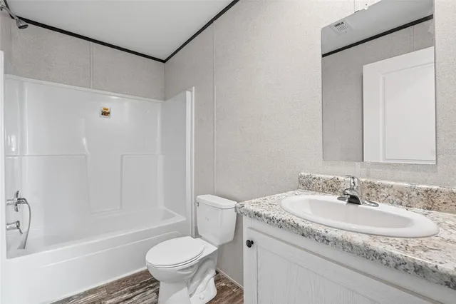 a bathroom with a granite countertop sink a toilet and shower