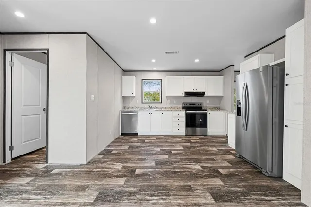 a kitchen with granite countertop a refrigerator and a stove top oven