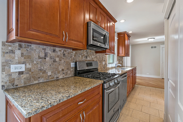 1617 Dundee Road Northbrook, IL 60062 - Photo 7 of 14 a kitchen with stainless steel appliances granite countertop a stove a sink and a microwave