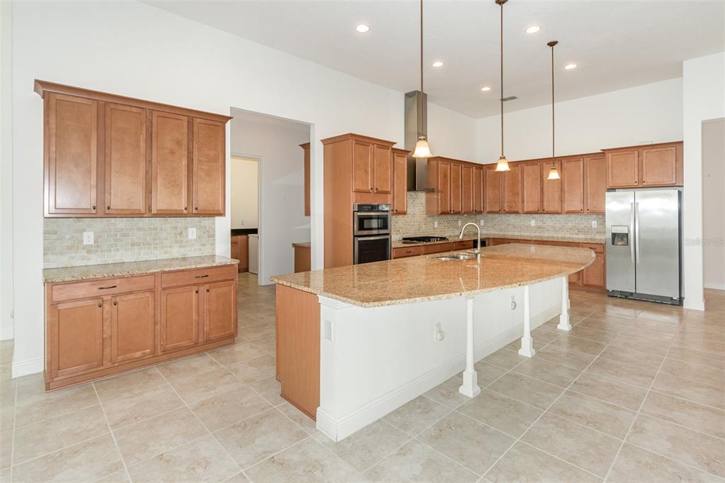 4911 Drawdy Court St. Cloud, FL 34772 - Photo 7 of 37 a large kitchen with kitchen island a large counter top stainless steel appliances and cabinets