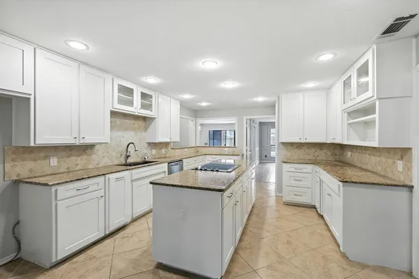 a kitchen with granite countertop a sink a stove and cabinets