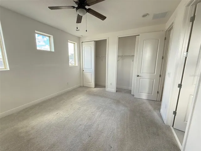 an empty room with windows and fan