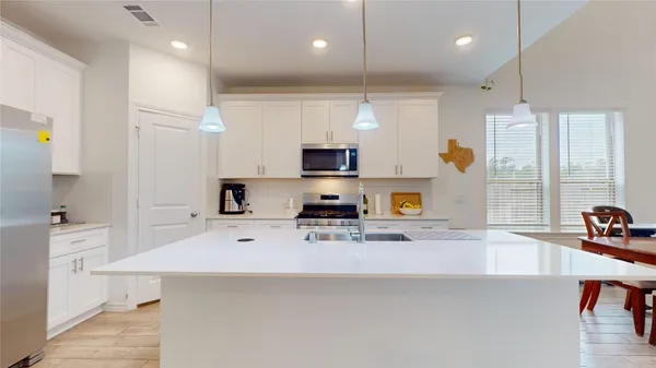 a view of a kitchen with kitchen island a sink stainless steel appliances and cabinets