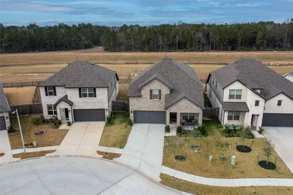 an aerial view of a house with swimming pool and trees in the background