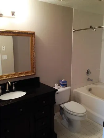 a bathroom with a granite countertop sink toilet a mirror and bathtub
