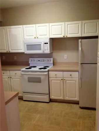 a kitchen with white cabinets and white appliances