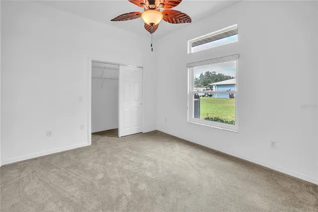 an empty room with a window and ceiling fan