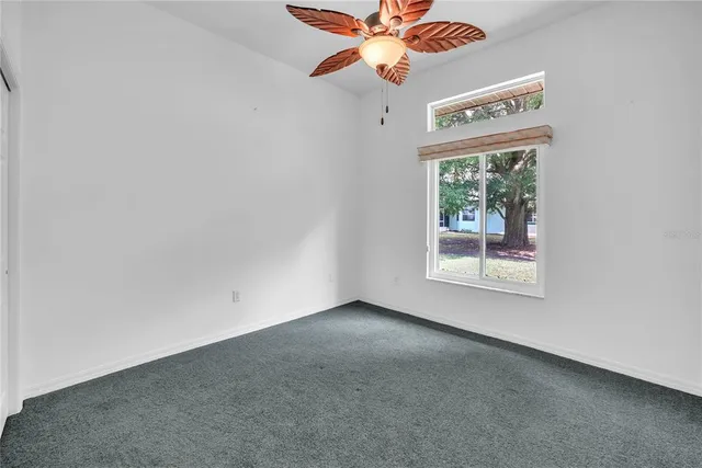 an empty room with a window and a fan
