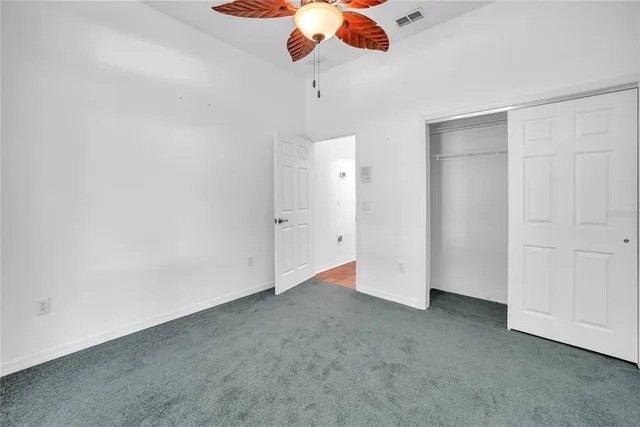 wooden floor in an empty room with a chandelier fan