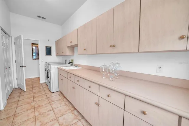 a kitchen with a sink dishwasher and white cabinets with wooden floor