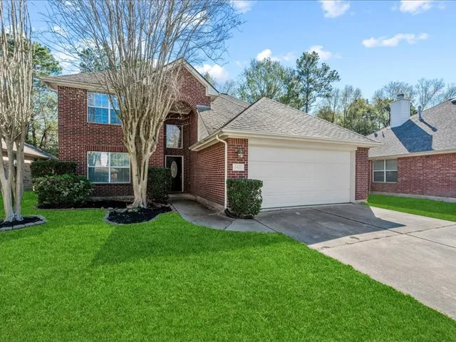 a view of a yard in front of a house with plants and large tree
