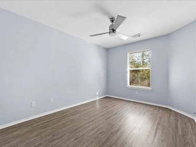 an empty room with wooden floor and windows