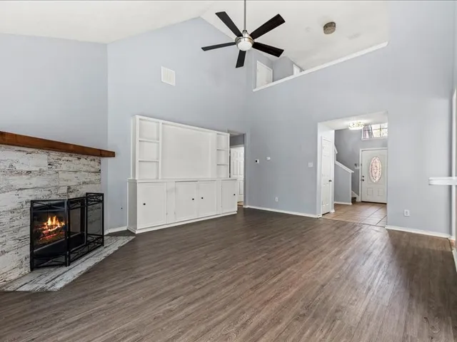 a view of an empty room with wooden floor fireplace and a window