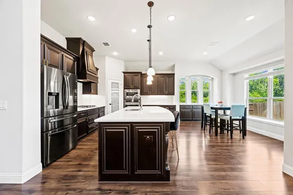 a kitchen with stainless steel appliances granite countertop a stove and a wooden floors