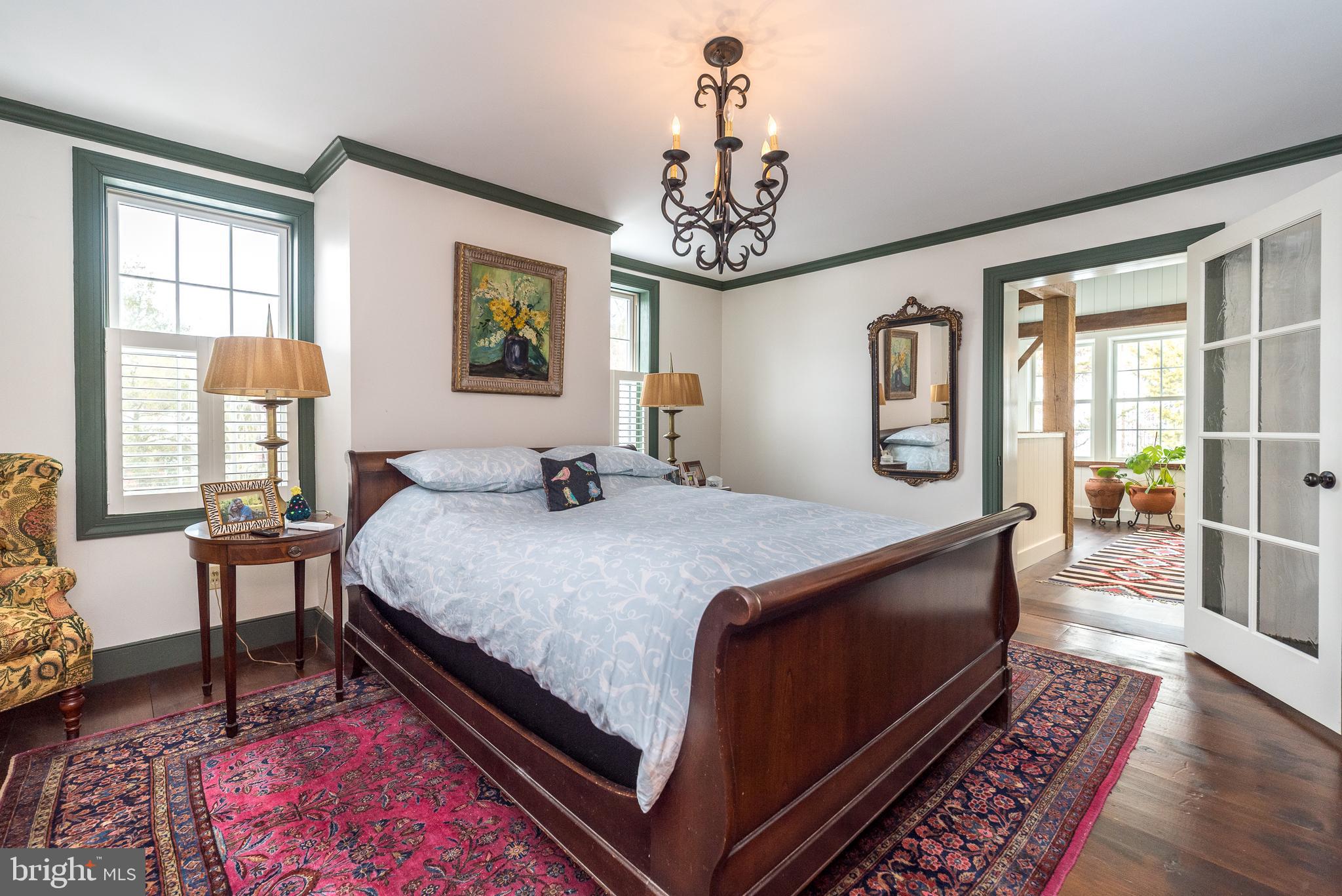 23 Lily Valley Road Erwinna, PA 18920 - Photo 40 of 81 a bedroom with a large bed a chandelier and windows
