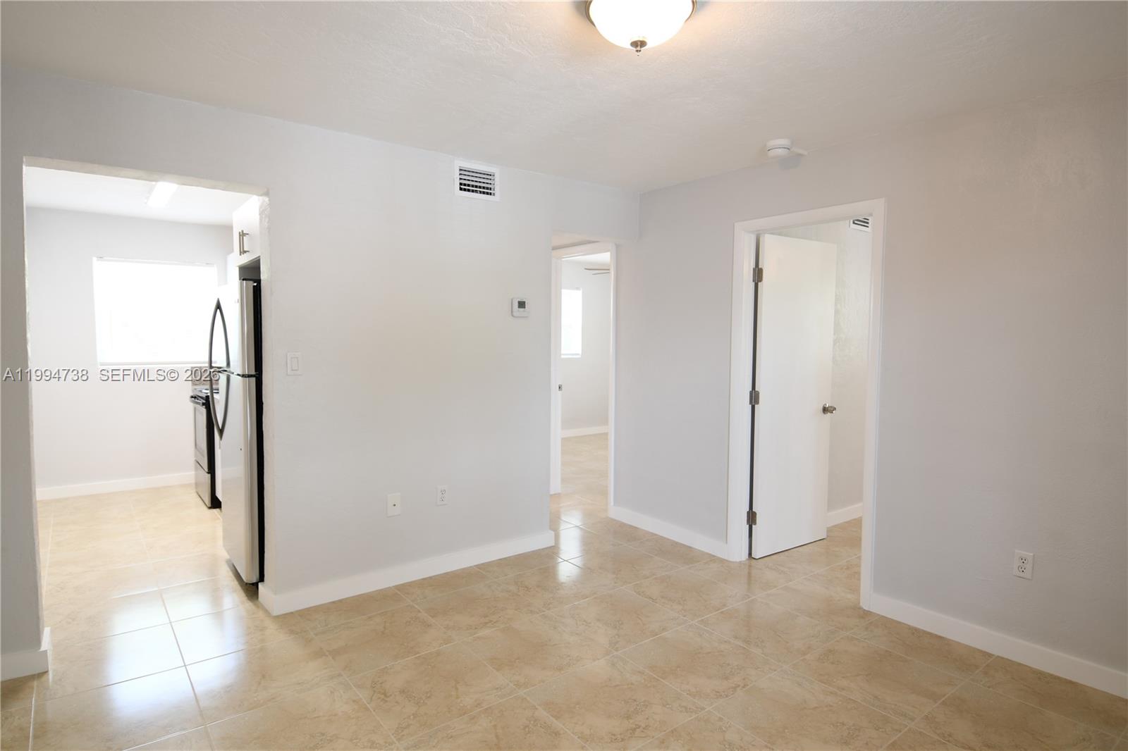 1398 Northwest 61st Street, Unit 10 Miami, FL 33142 - Photo 2 of 8 an empty room with sliding door and wooden floor