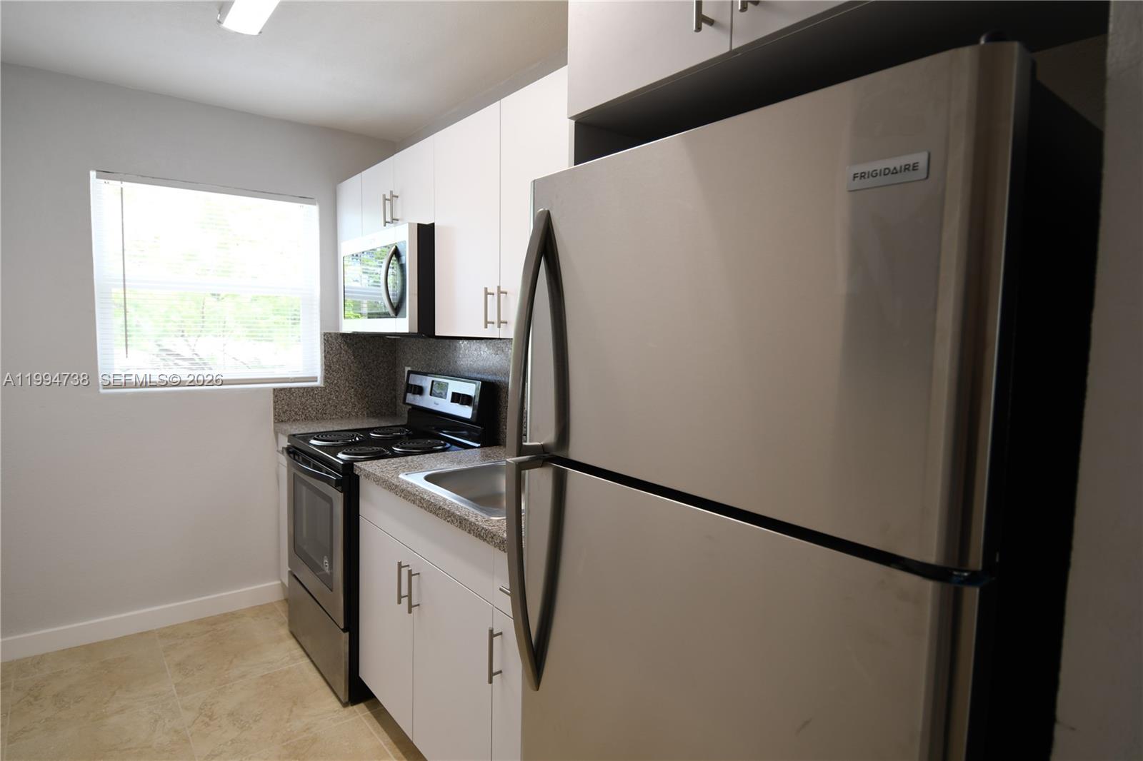 1398 Northwest 61st Street, Unit 10 Miami, FL 33142 - Photo 6 of 8 a kitchen with stainless steel appliances a refrigerator sink and stove