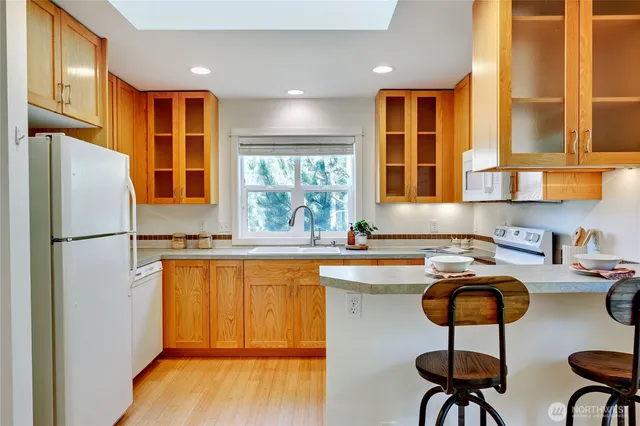 a kitchen with stainless steel appliances granite countertop a stove a refrigerator a sink a stove with island chairs and wooden floor