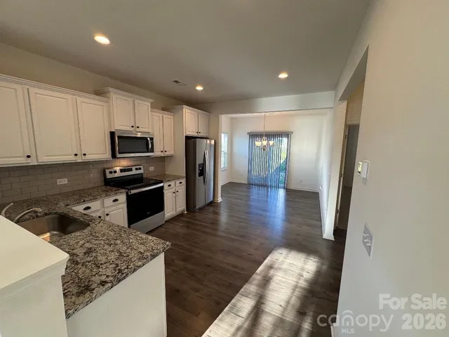 a kitchen with granite countertop a stove a sink and a refrigerator