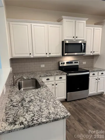 a kitchen with granite countertop a stove sink and cabinets