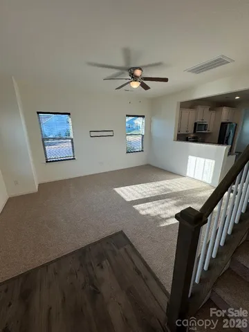 a view of kitchen and empty room with wooden floor