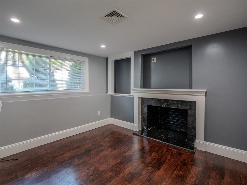 159 Mishawum Road Woburn, MA 01801 - Photo 31 of 41 an empty room with wooden floor fireplace and windows