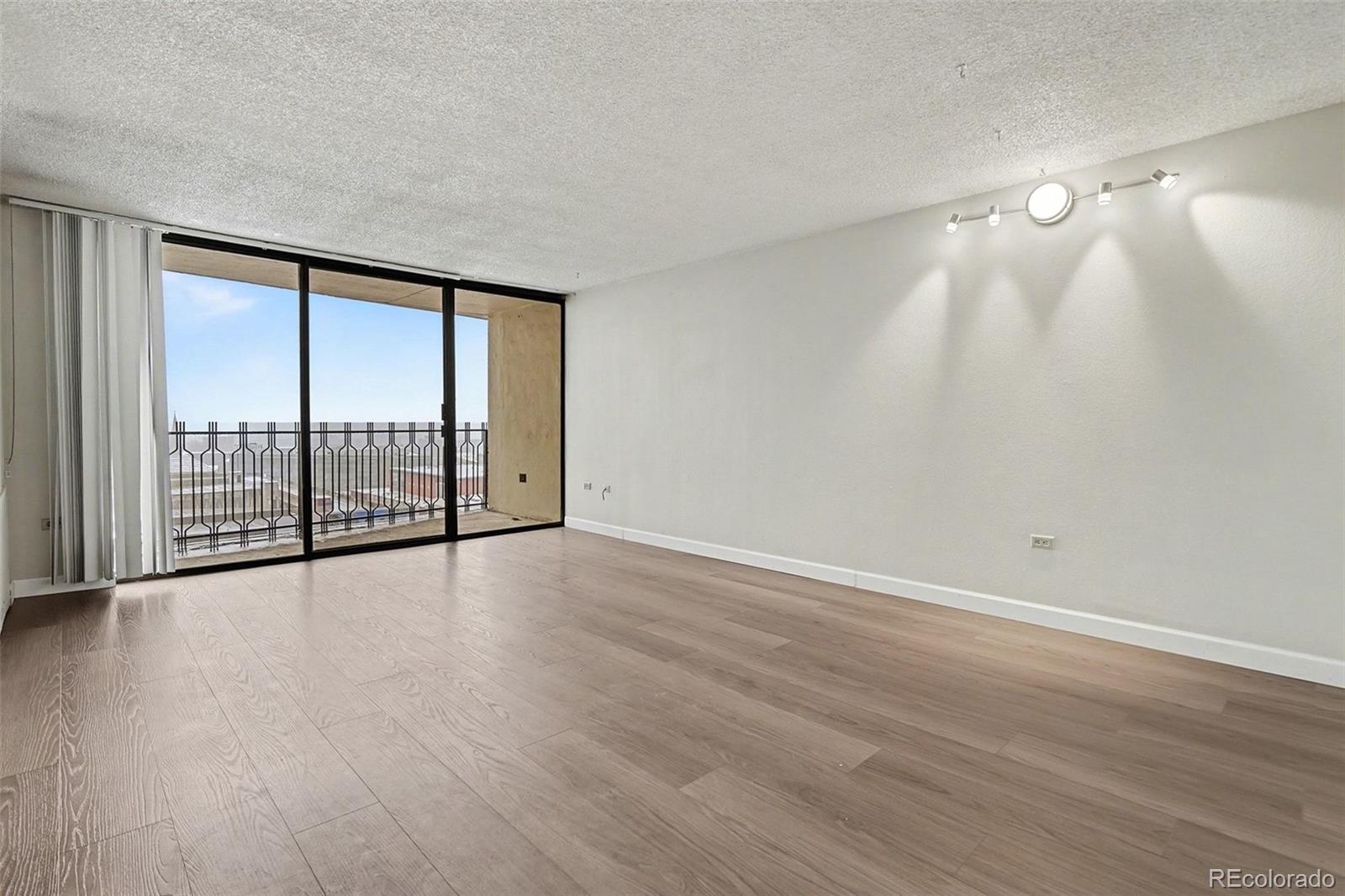1020 15th Street, Unit 13N Denver, CO 80202 - Photo 4 of 12 a view of an empty room with wooden floor and a window
