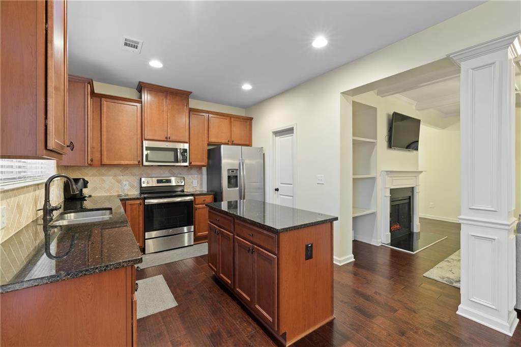 5715 Radford Loop Fairburn, GA 30213 - Photo 11 of 26 a kitchen with stainless steel appliances granite countertop a stove top oven a sink a refrigerator white cabinets and wooden floor