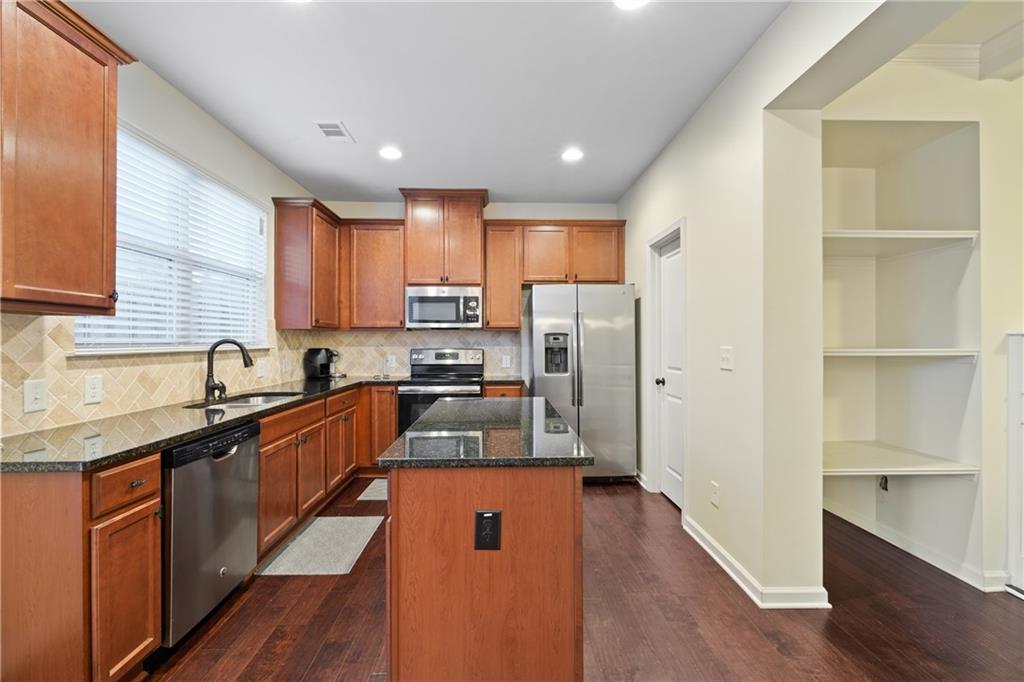 5715 Radford Loop Fairburn, GA 30213 - Photo 9 of 26 a kitchen with stainless steel appliances granite countertop a refrigerator a sink dishwasher a stove with wooden cabinets and wooden floor