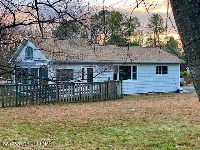 a view of a house with a large tree and wooden fence