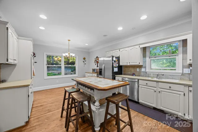 a kitchen with stainless steel appliances granite countertop table chairs sink and stove top oven