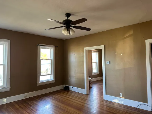 a view of an empty room with wooden floor and a window