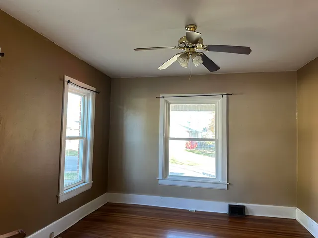 a view of an empty room with wooden floor and window