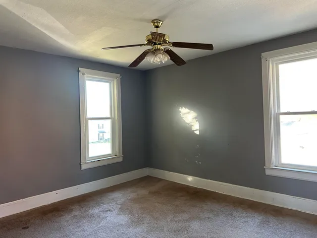 an empty room with a window and a chandelier fan