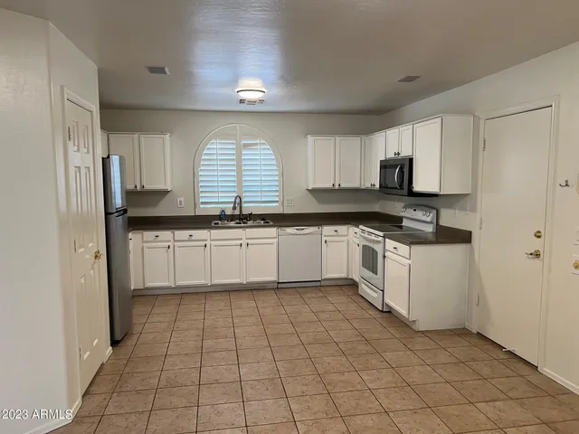 a white kitchen with a sink a stove a refrigerator and cabinets