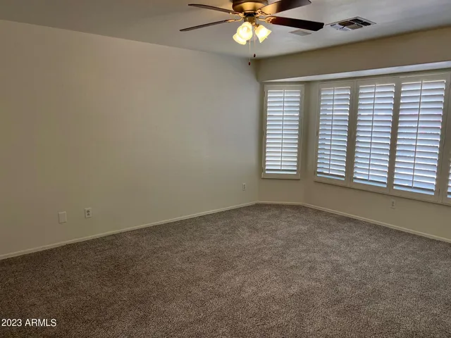 an empty room with a window and a fan