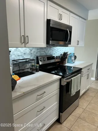 a kitchen with granite countertop white cabinets and stainless steel appliances