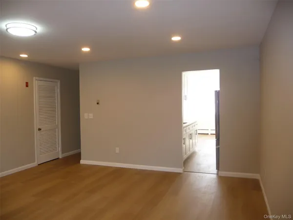 an empty room with wooden floor and mirror