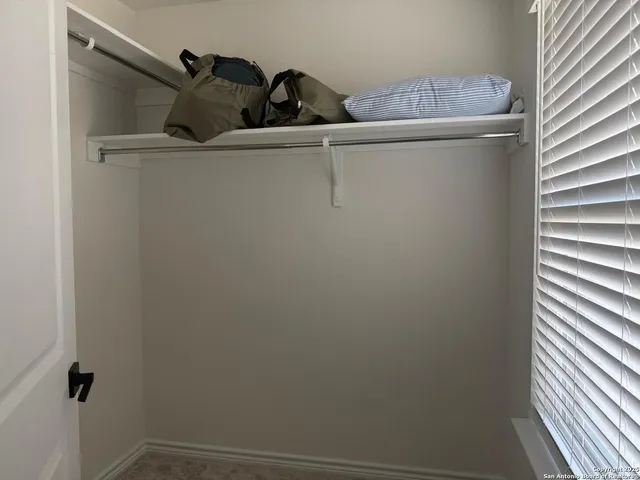 a bedroom with a bed and a potted plant on the dresser