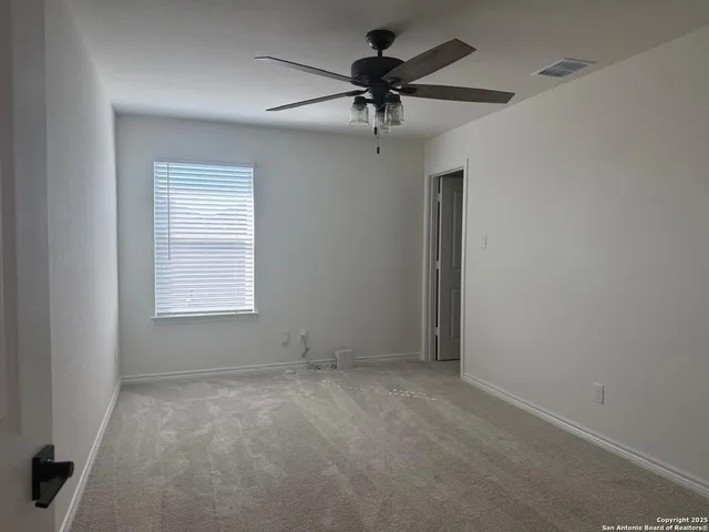 an empty room with a window and a fan