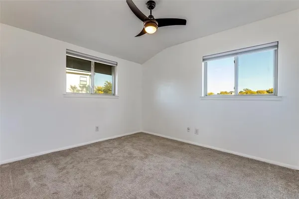 an empty room with windows and ceiling fan