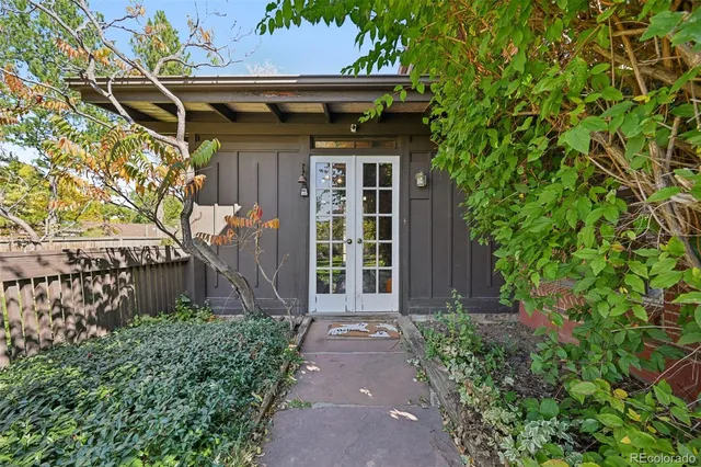 a view of a backyard with table and chairs potted plants and large tree