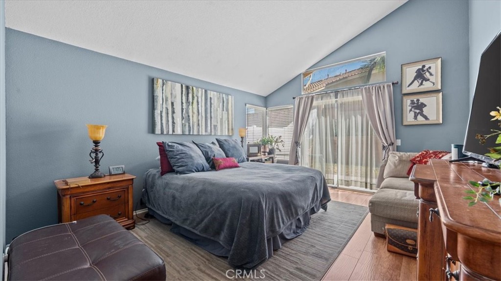 1671 Dominguez Ranch Road Corona, CA 92878 - Photo 19 of 42 A comfortable primary suite with vaulted ceilings, soft natural light, and direct access to the backyard through sliding glass doors, creating a peaceful retreat.