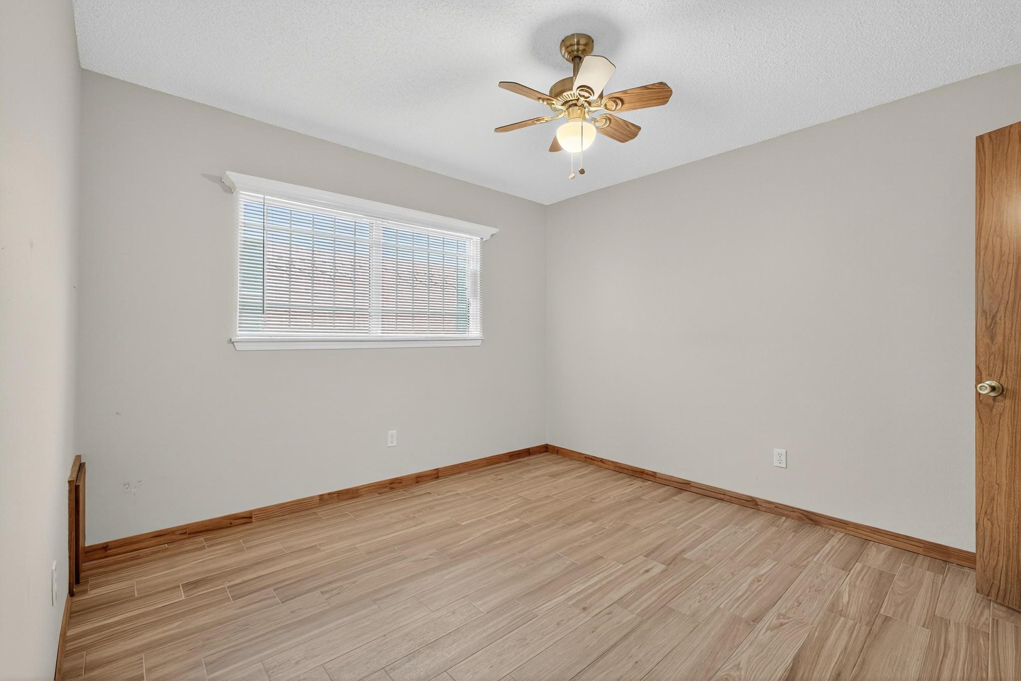 11803 Inga Lane Houston, TX 77064 - Photo 31 of 39 This room features light wood flooring, neutral walls, a ceiling fan with lights, and a window with blinds, providing a bright and airy space.